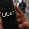 Una persona sosteniendo con las manos un celular donde se aprecian las letras de la aplicación de Uber.