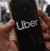Una persona sosteniendo con las manos un celular donde se aprecian las letras de la aplicación de Uber.