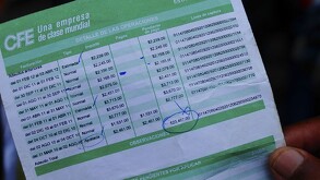 Se observa un recibo verde de la Comisión Federal de Electricidad y un dedo de una mano sujetándolo.