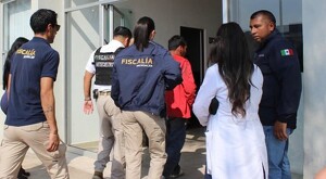 Elementos de la Fiscalía del Estado de Michoacán portando sus uniformes y escoltando al comerciante rescatado que camina en medio y viste una playera roja