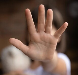 Se observa la mano de una niña y no se le ve el rostro ya que se tapa con la mano.