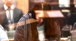 Madre identificada como Hakyung Lee, mostrándose cabizbaja detrás de un cristal de seguridad durante el juicio en una corte de Nueva Zelanda