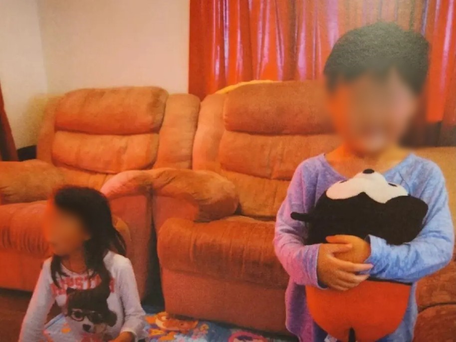 A la derecha: la niña Yuna Jo sentada en un tapete para niños. A la izquierda: el niño Minu Jo sosteniendo un peluche de Mickey Mouse