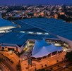 Vista aérea nocturna de la Expo Guadalajara, el gran centro de convenciones y exposiciones, con su icónico techo abovedado iluminado en el centro.