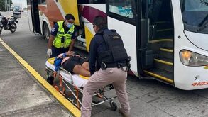 Dos paramédicos auxiliando a una mujer junto a un autobús de la línea AU.