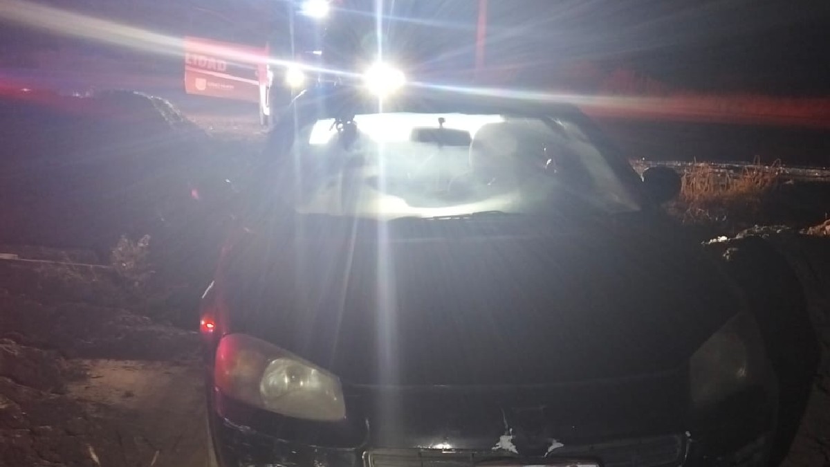 Auto en color negro estacionado y con las luces encendidas