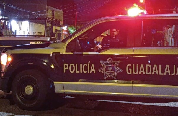 Patrullas y elementos de la Policía de Guadalajara junto a una cinta policiaca que acordona el perímetro de la escena del crimen con casas alrededor