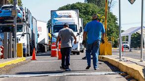 Dos personas en una autopista junto a varios tractocamiones.