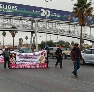 Se ven personas caminando sobre un bulevar con una pancarta en las manos.