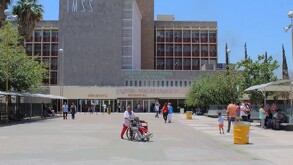 Edificio del IMSS en color verde rodeado de decenas de personas