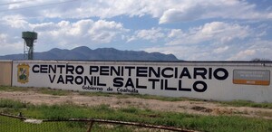 Hay una  barda pintada de blanco con letras que dicen Centro Penitenciario Varonil Saltillo.