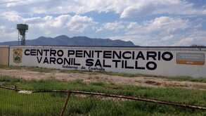 Hay una  barda pintada de blanco con letras que dicen Centro Penitenciario Varonil Saltillo.