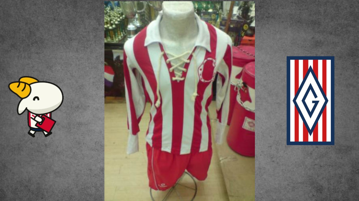 Una exhibición de la historia de Chivas en un museo, mostrando cinco camisetas históricas del club en vitrinas transparentes, con una foto del equipo campeón de