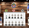 Un gabinete de trofeos del Club Deportivo Guadalajara (Chivas) con copas, balones y fotos polaroid de celebraciones del equipo sobre un fondo de madera.