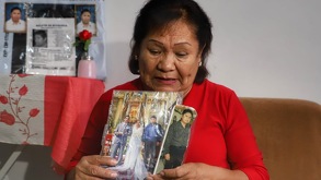 una mujer sostiene unas fotografías de su hijo desaparecido en puebla