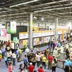 Multitud de personas recorriendo los pasillos dentro de la Expo Guadalajara con carteles, stands, libros y carteles