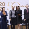 Una fila de seis personas vestidas de forma formal en el escenario. Una mujer en el centro recibe un premio de otra mujer (posiblemente Claudia Sheinbaum), cele