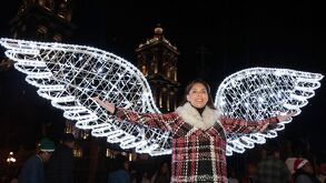 Mujer posando en el alumbrado navideño colocado frente a la catedral en el Centro Histórico de Puebla.