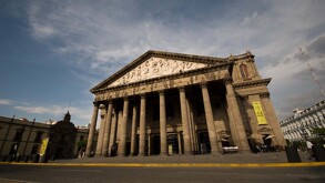 Vista en contrapicado del Teatro Degollado en Guadalajara. El edificio neoclásico tiene un gran pórtico de columnas dóricas y un frontón con un bajorrelieve.