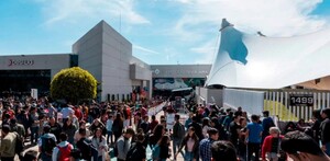 Una gran multitud de personas (visitantes de la FIL) afuera del edificio de la Expo Guadalajara bajo el sol. El edificio principal tiene una carpa blanca grande