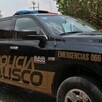 Vista lateral de una patrulla de la Policía del Estado de Jalisco estacionada con árboles y un edificio de color rojo de fondo