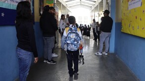 un niño con mochila entra caminando a su escuela
