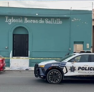 Está una fachada con letrero que dice Iglesia Berea Saltillo, pintada de color verde, y se ve una persona en el piso cubierta con una cobija.