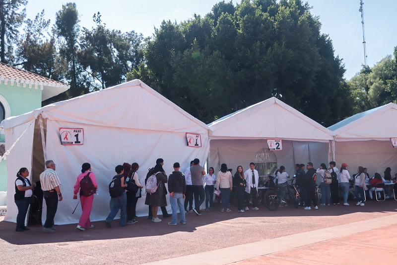 Personas haciendo una fila para ingresar a carpas blancas para la prueba rápida de detección de VIH.