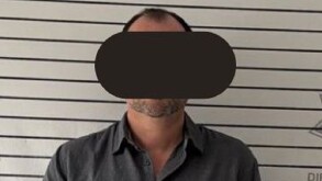 Se observa a un hombre con ojos tapados y vistiendo una playera color gris.