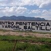 Hay una  barda pintada de blanco con letras que dicen Centro Penitenciario Varonil Saltillo.