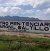 Hay una  barda pintada de blanco con letras que dicen Centro Penitenciario Varonil Saltillo.