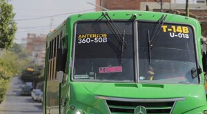 Vista frontal de un camión color verde de la ruta 50B circulando por calles de Guadalajara con casas y autos alrededor