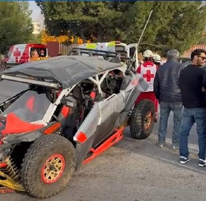 Se observa un RZr gris con rojo y jóvenes parados a lado de éste.