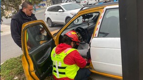 Se observa un taxi y adentro a una persona, mientras un paramédico trata de ayudarlo.