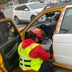 Se observa un taxi y adentro a una persona, mientras un paramédico trata de ayudarlo.