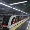 Un moderno tren del Tren Ligero de Guadalajara (blanco y rojo) espera en una estación subterránea limpia con pisos reflectantes, escaleras de mármol negro y luc