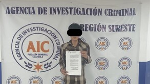 Se ve a un joven con ojos cubiertos, atrás hay un letrerro que dice Agencia de Investigación Criminal.
