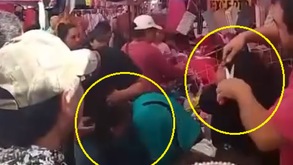 Hombres cortando con tijeras y cuchillo el cabello de dos mujeres en un mercado de Puebla.