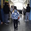 un niño con mochila entra caminando a su escuela