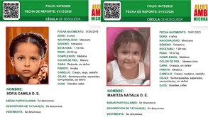 Dos trabajadores con cascos amarillos inspeccionan un arroyo con un barril azul y un tubo de drenaje de terracota. Se aprecia una cruz negra con la inscripción