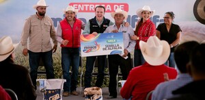 Esteban Villegas y Susy Torrecillas sonríen junto a productores recibiendo un vale de semilla de alfalfa. El vale es de tamaño grande y simbólico del apoyo.
