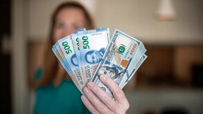 Mujer sosteniendo dólares estadounidenses y billetes mexicanos.