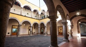 Arcos, columnas y pasillos dentro del Museo de la Ciudad de Guadalajara con paredes amarillas y un espacio libre al centro