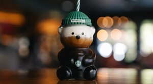 Vaso Bearista de Starbucks rellenos de café con leche sobre una mesa de madera y con un fondo difuminado