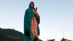 Imagen de la Virgen de Guadalupe con las manos sobre el pecho en lo alto de un cerro de Puebla.