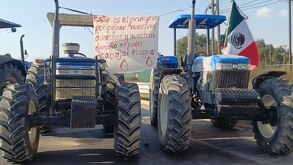 Tractores con un mensaje de protesta bloqueando el paso en una carretera de Puebla.