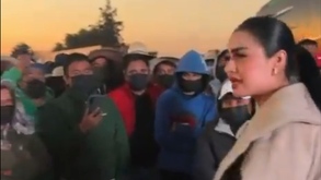 Mujer dialogando con un grupo de manifestantes cubiertos del rostro.