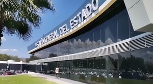 Vista de la fachada exterior de la Fiscalía General del Estado de Michoacán con automóviles estacionados alrededor y una persona caminando