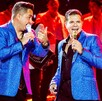 Se ven a dos hombres vestidos con saco azul brillante cantando.