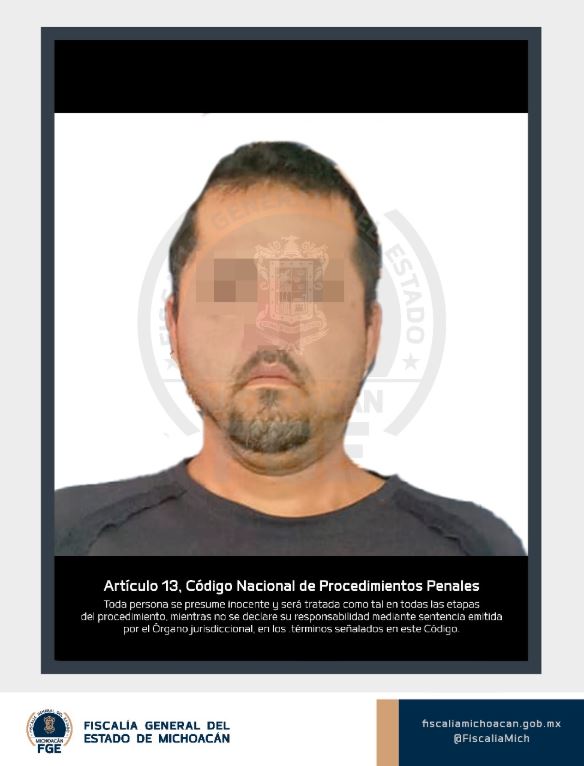 Yhonatan ‘N’ viendo de frente con los ojos censurados, vistiendo una playera gris oscuro con un fondo blanco durante su detención